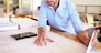 Male Architect With Digital Tablet Studying Plans In Office