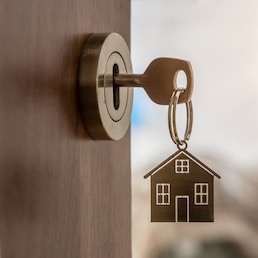 Open door to a new home with key and home shaped keychain. Mortgage, investment, real estate, property and new home concept