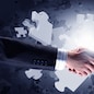 Close up of business handshake with puzzle elements at background