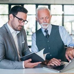 Focused senior and young colleagues discussing project.