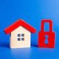 A wooden house and a red padlock. Unavailable and expensive real estate. house Insurance. Security and safety. Confiscation for debts. alarm system. seizure of property. Protection of property rights.