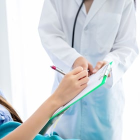Close-up of female patient Signature for consent form on bed to doctor in the room hospital background.