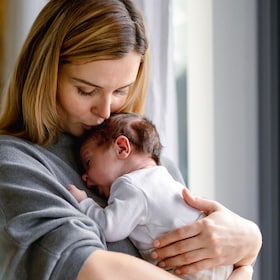 Loving mother hugs her little baby at home