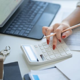 hand of accountant using a calculator on the workplace, calculator and plant potted on white desk background, Accounting workplace concept