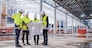 Front view of group of engineers with blueprints standing on construction site.