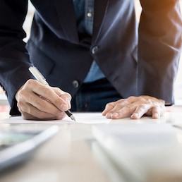 Businessman writing in a document. Focus on the tip of the pen.