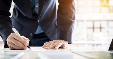 Businessman writing in a document. Focus on the tip of the pen.