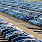Rows of a new cars parked in a distribution center on a car factory on a sunny day. Top view to the parking in the open air.