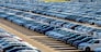 Rows of a new cars parked in a distribution center on a car factory on a sunny day. Top view to the parking in the open air.