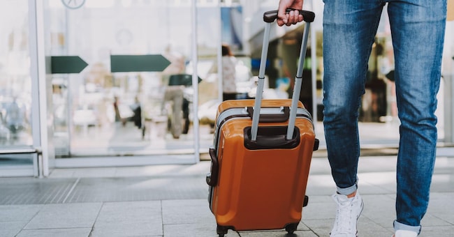 Close-up of man walking with suitcase. He is going in departure lounge. Copy space in left side