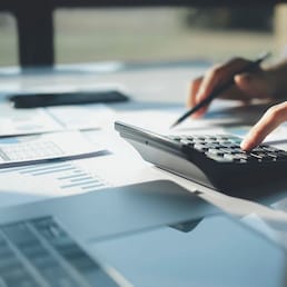 Businessman accountant using a calculator and laptop computer while counting and discussing taxes with a client. Business audit and finance concepts