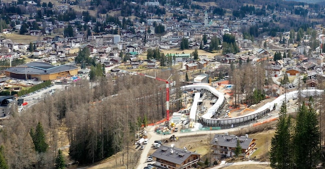 Una veduta aerea del nuovo Centro di Scivolamento di Cortina nel giorno dei test di pre-approvazione in vista dei Giochi Olimpici Invernali Milano Cortina 2026, con Cortina d'Ampezzo sullo sfondo, il 25 marzo 2025. La lunga saga delle Olimpiadi 2026 è finalmente giunta al termine: a poco più di due mesi dai Giochi Olimpici, la pista di bob di Cortina d'Ampezzo ospiterà la sua prima gara il 21 novembre 2025. (Foto di Andrea BERNARDI / AFP)