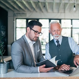 Focused senior and young colleagues discussing project.