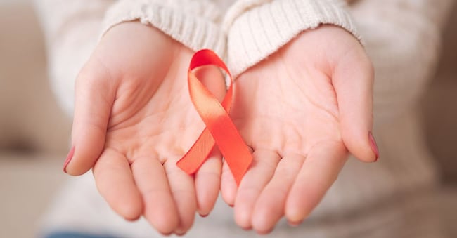 Stop AIDS. Close up of a small red AIDS ribbon being in the womans hands