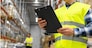 logistic business, shipment and people concept - close up of male worker or supervisor with clipboard in reflective safety vest at warehouse
