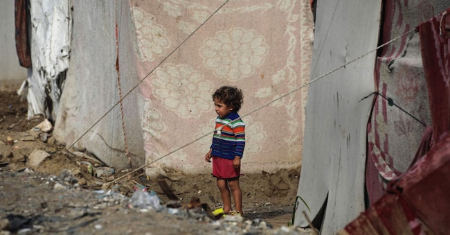 Un bambino tra i rifugi di fortuna del campo di Nuseirat per sfollati palestinesi nella Striscia di Gaza centrale. L’Unicef stima che ad oggi oltre 9.000 bambini sono a rischio malnutrizione acuta nella Striscia di Gaza. (Photo by Eyad Baba / AFP)