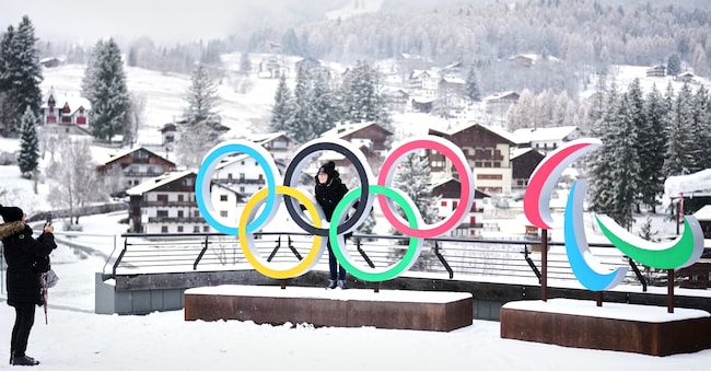 Persone scattano foto davanti agli anelli delle Olimpiadi e Paralimpiadi invernali di Milano Cortina, a Cortina D'Ampezzo, giovedì 20 novembre 2025. (Foto AP/Andrew Medichini)