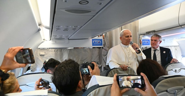 Papa Leone XIV risponde ai giornalisti accanto al portavoce della Sala Stampa vaticana Matteo Bruni a bordo del volo diretto a Beirut, in Libano, il 30 novembre 2025. - ANSA/Andreas SOLARO / POOL / AFP