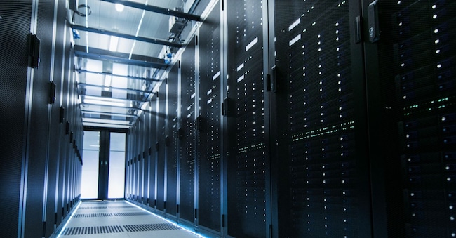 Ripresa di un Data Center funzionante con file di server rack. Le persone che camminano e lavorano sono sfocate in movimento. Ripresa a lunga esposizione (Alamy Stock Photo)