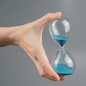 Woman holding an hourglass on a gray background. Close-up. Copy space