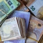 Bundles of European banknotes tied with rubber bands.