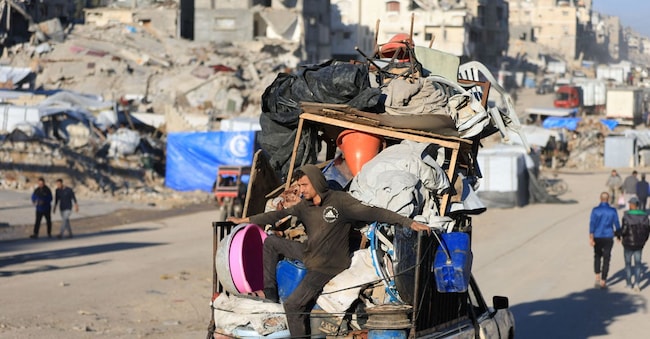 Un uomo viaggia su un pick-up carico di effetti personali e passa davanti a edifici danneggiati a Gaza City, 2 dicembre 2025. REUTERS/Dawoud Abu Alkas