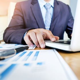 Working process startup. Businessman working with new finance project at office with laptop, tablet and graph data documents on his desk