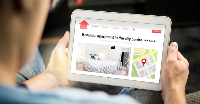 L'uomo cerca appartamenti e case online con un dispositivo mobile. Sito web o applicazione per l'affitto di case per le vacanze o per il settore immobiliare. 