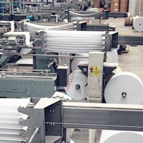 A industrial commercial envelope making machine, making paper envelopes for international distribution. Automated engineering machinery for mass production of paper envelopes.