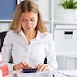 Young business woman calculates tax at desk in office