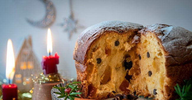 A traditional panettone, the famous italian Christmas cake on a table. Blurred Christmas tree and decoration on background