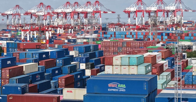 Una veduta aerea mostra i container impilati al terminal container del porto di Shanghai l'8 dicembre 2025. Le esportazioni cinesi sono cresciute più velocemente del previsto il mese scorso, secondo i dati ufficiali dell'8 dicembre, tornando a crescere dopo la flessione di ottobre, nonostante il forte calo delle spedizioni verso gli Stati Uniti. (Foto di -STR / AFP) / Cina OUT