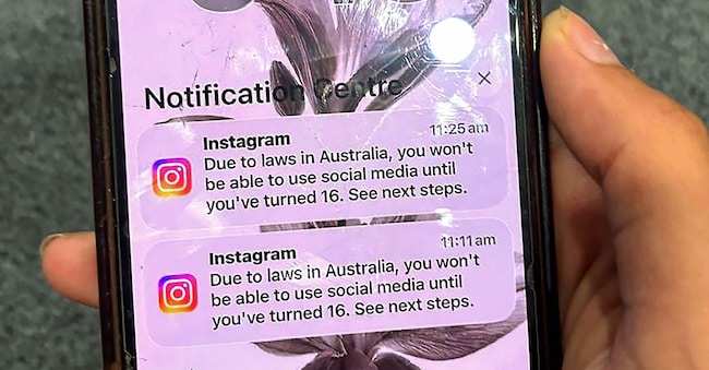 Un adolescente tiene in mano un cellulare che mostra un messaggio della piattaforma di social media Instagram dopo che l'account è stato bloccato per la verifica dell'età a Sydney (Foto di AFP)