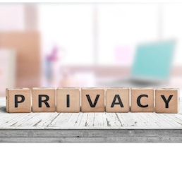 Privacy sign on a wooden table in a bright room with a computer