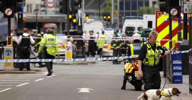 Un poliziotto utilizza un cane anti-bomba per perlustrare un'area vicino alla stazione della metropolitana di Warren St, a Londra, dopo un'esplosione, il 21 luglio 2005. Esplosioni separate in tutta Londra hanno avuto luogo alla stazione della metropolitana di Warren St, alla stazione della metropolitana di Oval, alla stazione della metropolitana di Sepherds Bush e a Hackney road. Le esplosioni sono avvenute in seguito agli attacchi terroristici ai sistemi di trasporto londinesi del 17 luglio 2005. (Foto di Carl De Souza / AFP)