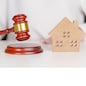 Real Estate Law, Home Insurance, property Tax, Auction and Bidding concepts. small toy house model with gavel justice hammer on desk in courthouse