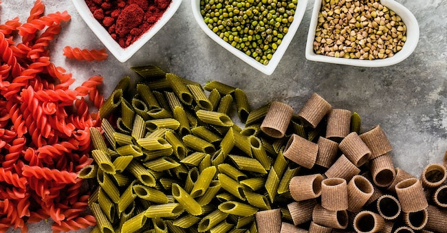 Pasta  senza glutine con ingredienti in ciotole a forma di cuore da cui viene ricavata su un tavolo di pietra