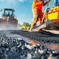 Road construction workers' teamwork, tarmac laying works at a road construction site, hot asphalt gravel leveled by workers, and road surface repair.