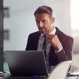 Laptop, thinking and boardroom with a businessman at work on research for future company growth. Computer, idea and innovation with a male employee or manager in his office with review his strategy.