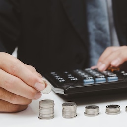 businessman person hand holding coin stack money and calculator on desk.business finance tax growth investment accounting insurance concept