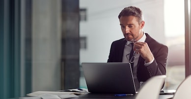 Laptop, thinking and boardroom with a businessman at work on research for future company growth. Computer, idea and innovation with a male employee or manager in his office with review his strategy.