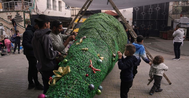 I parrocchiani palestinesi addobbano l’albero di Natale nella chiesa cattolica della Sacra Famiglia a Gaza City, martedì 23 dicembre 2025, in vista delle celebrazioni natalizie. (AP Photo/Jehad Alshrafi)