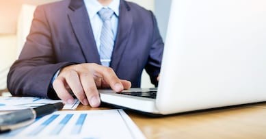 Working process startup. Businessman working with new finance project at office with laptop, tablet and graph data documents on his desk
