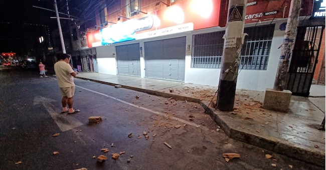 Persone in piedi vicino alle macerie della facciata di una casa dopo un terremoto a Chimbote, in Perù