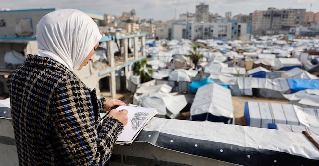 Sarah Saada, quindicenne palestinese sfollata, fuggita da Beit Lahia, nel nord della Striscia di Gaza, durante i bombardamenti israeliani, disegna mentre si trova accanto alla sua tenda che domina un campo per sfollati a Gaza City, il 30 dicembre 2025. A partire da ottobre, un fragile cessate il fuoco ha finora fermato due anni di guerra tra Israele e Hamas nella Striscia di Gaza, nonostante entrambe le parti si siano scambiate accuse di violazione della tregua. (Foto di Omar AL-QATTAA / AFP)