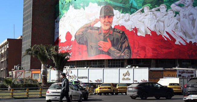 Gli iraniani camminano davanti a un enorme striscione dell'ex comandante della Forza Quds del Corpo delle Guardie Rivoluzionarie Islamiche (IRGC) Qasem Soleimani in vista del sesto anniversario del suo assassinio a Piazza Valiasr a Teheran, Iran, il 30 dicembre 2025.  EPA/ABEDIN TAHERKENAREH