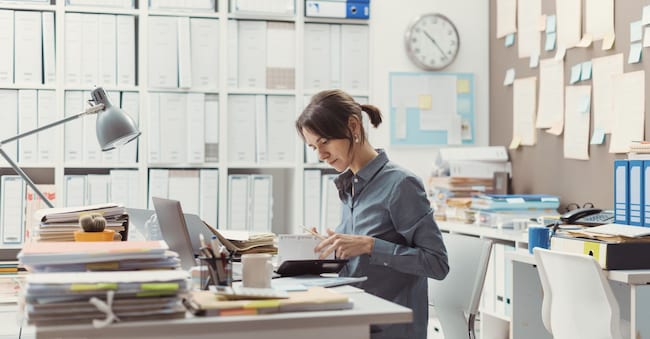 Efficient female office clerk sitting at desk in the office and working