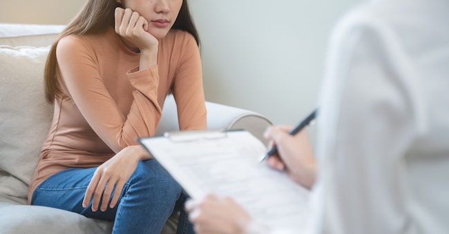 Young woman in a mental therapy session talking with a psychologist in the office. Pormezz - stock.adobe.com