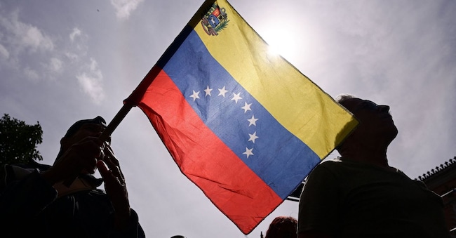 Una persona tiene in mano una bandiera venezuelana mentre i sostenitori del governo si riuniscono dopo gli Stati Uniti. Il presidente Donald Trump ha dichiarato che gli Stati Uniti hanno colpito il Venezuela e catturato il loro presidente Nicolas Maduro, a Caracas, Venezuela, il 3 gennaio 2026. REUTERS/Gaby Ora