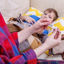 Mother checking the temperature of her ill baby with a thermometer.